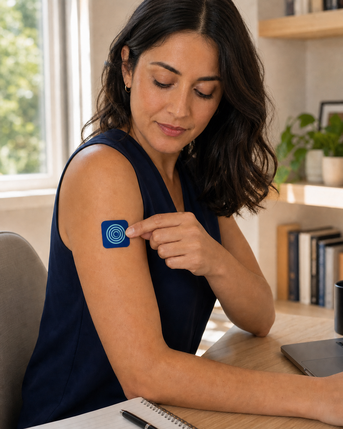 The same woman placing a Focus Patch on her left upper arm