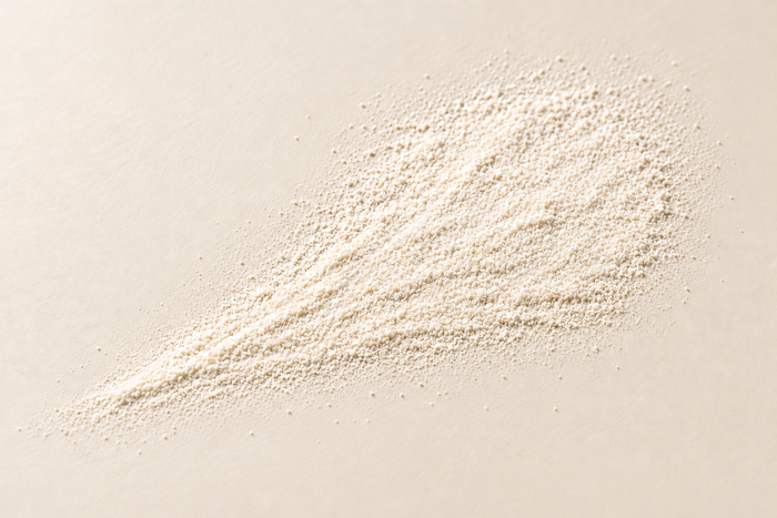 A flat fan of fine off-white powder on ivory, illustrating NAC.