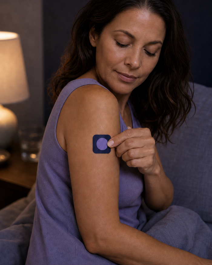 A woman placing one Pure Patch Sleep Patch on her upper arm