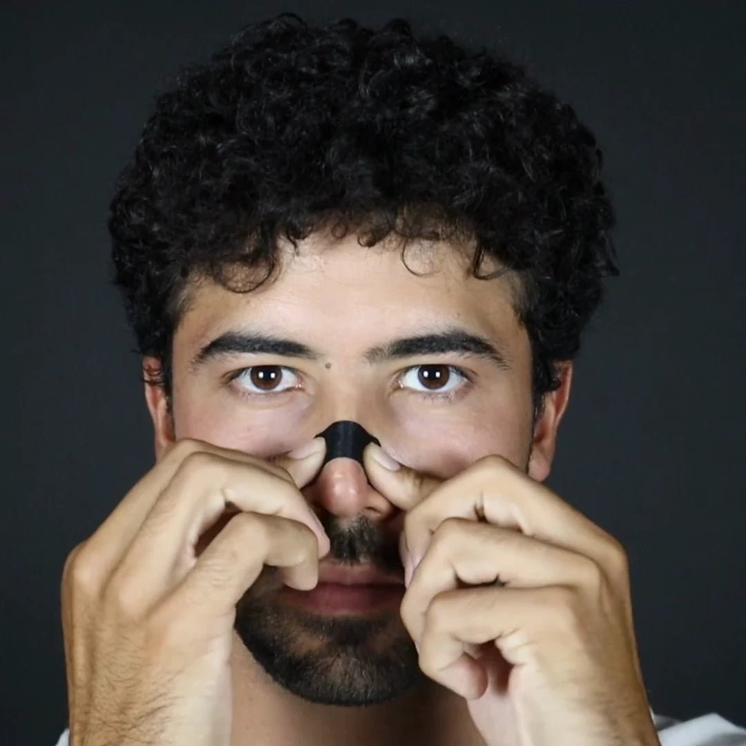 A man pressing the ends of a Pure Patch Nose Strip onto the sides of his nose.